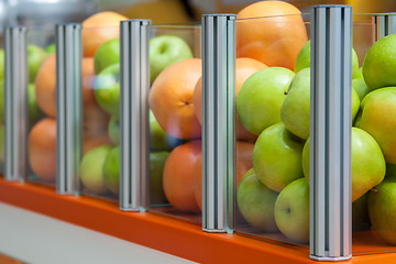 Image showing Glass showcase with fresh fruit apples and oranges, focus is positioned on apples