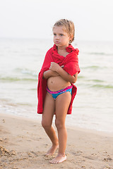 Image showing Frozen five year old girl wrapped in an adult t-shirt standing on a sea shore