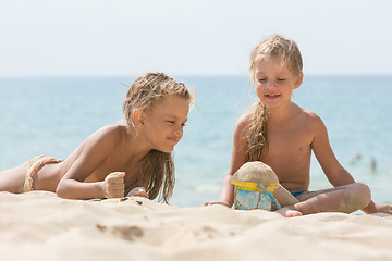 Image showing Two little girls are playing with enthusiasm in the sand on the seashore