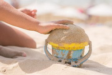 Image showing Childrens pen in the bucket pours sand on the beach