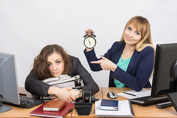 Image showing The girl in the office with a smile, indicating the hours and tortured colleague