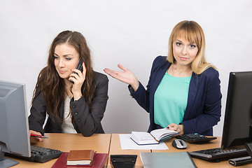 Image showing The girl in the office puzzled indicates colleague talking on the phone