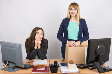 Image showing The girl in the office is facing the box with things near the colleague sitting next