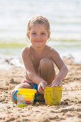 Image showing Glad kid playing on a sandy beach with a pond and sand molds