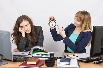 Image showing  Office workers at the end of the day, one with a smile indicates a clock, another weary head props