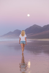 Image showing Lady walking on sandy beach in sunset.