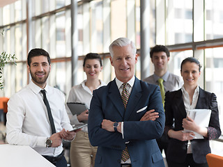 Image showing portrait of senior businessman as leader  with staff in backgrou