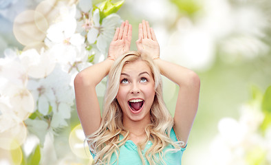 Image showing happy smiling young woman making bunny ears