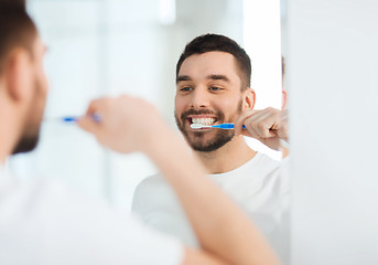 Image showing man with toothbrush cleaning teeth at bathroom