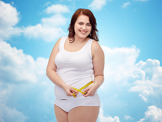 Image showing happy young plus size woman with measuring tape