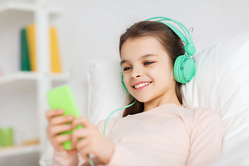 Image showing happy girl lying in bed with smartphone at home