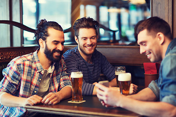 Image showing male friends with smartphone drinking beer at bar