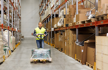 Image showing man carrying loader with goods at warehouse