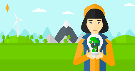 Image showing Woman with lightbulb and trees inside.