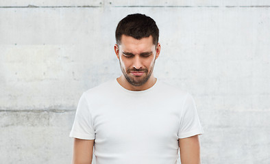 Image showing unhappy young man over gray wall background