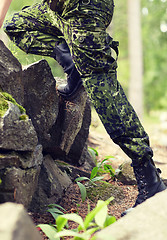 Image showing close up of soldier climbing on rocks in forest