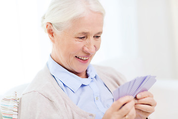 Image showing happy senior woman playing cards at home