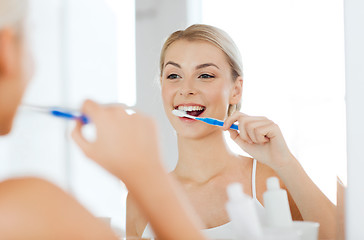 Image showing woman with toothbrush cleaning teeth at bathroom