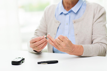 Image showing senior woman with glucometer checking blood sugar