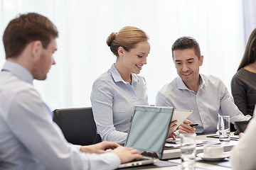 Image showing smiling business people with tablet pc in office