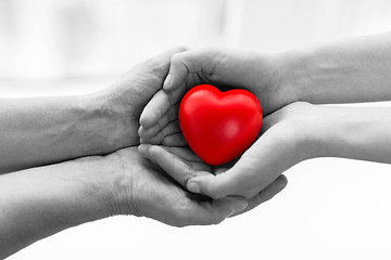 Image showing senior and young woman hands holding red heart