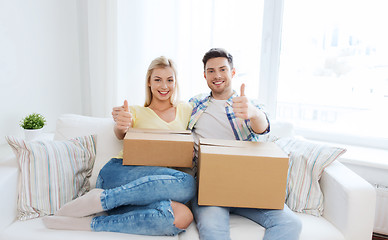 Image showing happy couple with boxes showing thumbs up at home