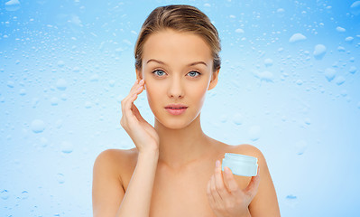 Image showing young woman applying cream to her face