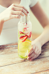 Image showing close up of woman with fruit water in glass bottle