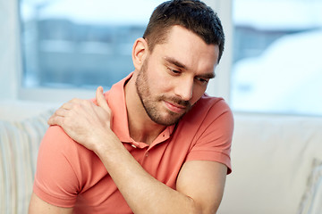 Image showing unhappy man suffering from neck pain at home