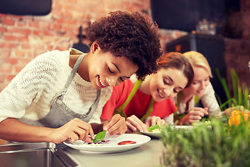 Image showing happy women cooking and decorating dishes