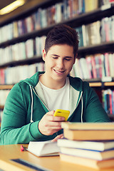 Image showing male student with smartphone texting in library