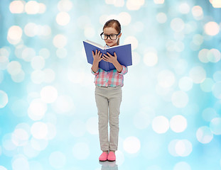 Image showing happy little girl in eyeglasses reading book