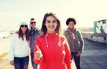 Image showing happy teenage friends showing thumbs up on street