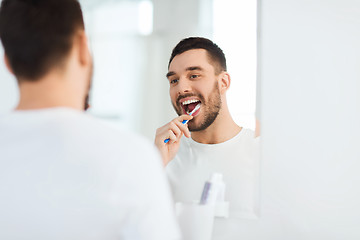 Image showing man with toothbrush cleaning teeth at bathroom