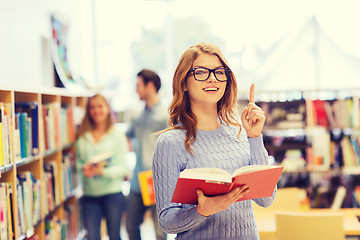 Image showing happy student girl or woman with book in library