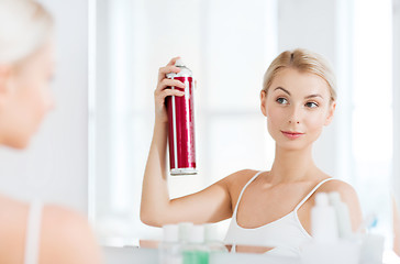 Image showing woman with hairspray styling her hair at bathroom