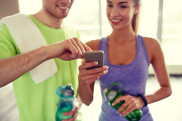 Image showing happy woman and trainer showing smartphone in gym