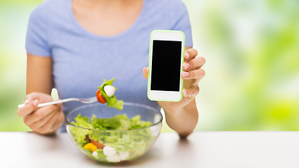 Image showing close up of woman with smartphone eating salad