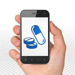 Image showing Healthcare concept: Hand Holding Smartphone with Pills on display