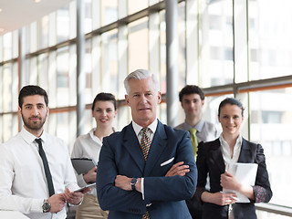 Image showing portrait of senior businessman as leader  with staff in backgrou