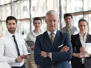 Image showing portrait of senior businessman as leader  with staff in backgrou