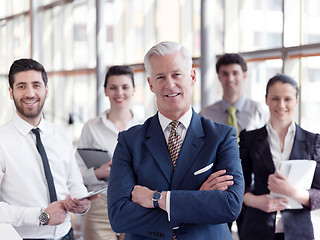 Image showing portrait of senior businessman as leader  with staff in backgrou