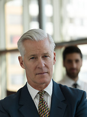 Image showing portrait of senior businessman as leader  with staff in backgrou