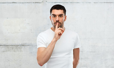 Image showing young man making hush sign over gray wall