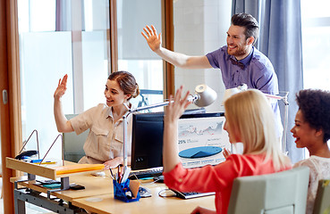 Image showing happy creative team waving hands in office