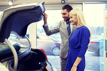 Image showing happy couple with car dealer in auto show or salon