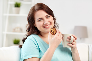 Image showing happy plus size woman with cup and cookie at home