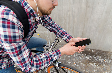 Image showing hipster man in earphones with smartphone and bike