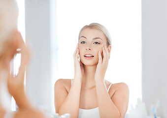 Image showing happy young woman looking to mirror at bathroom