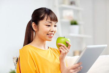 Image showing happy asian woman with tablet pc and apple at home